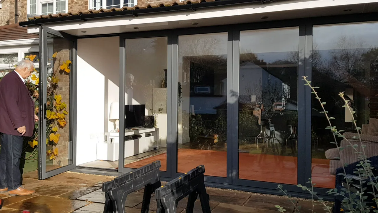 De OpenGlide-toegangsdeur staat open naar het terras, terwijl de overige glazen panelen gesloten blijven