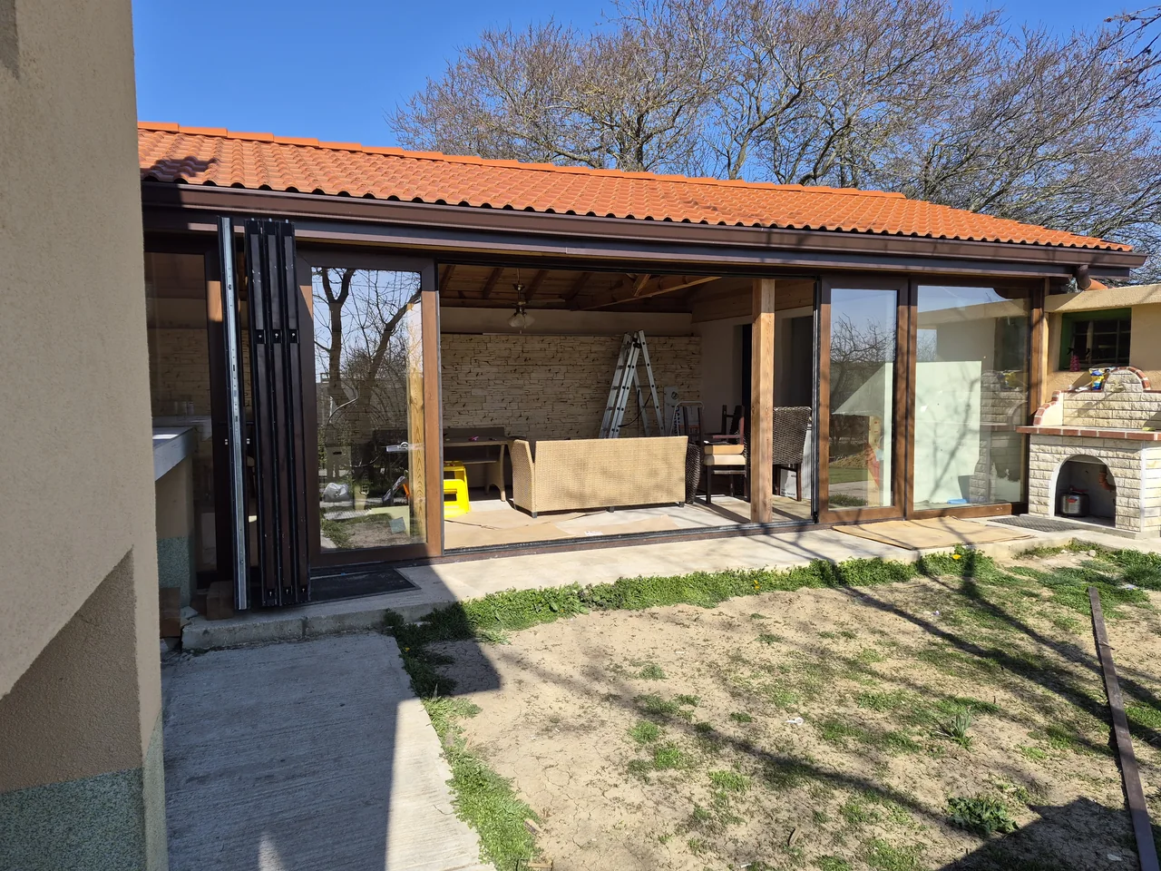 OpenGlide-panelen met houtlook, die naast een brede centrale opening naar een tuinveranda zijn samengetrokken